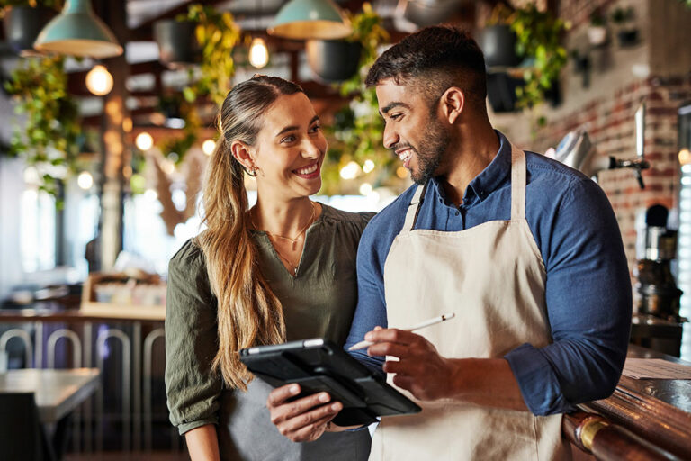 Deux jeunes entrepreneurs souriants consultant une tablette dans leur commerce